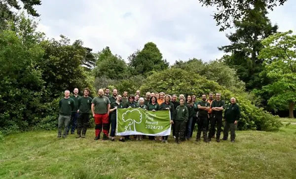 Epping Forest staff photo holding Green Flag Award Flag in the Forest