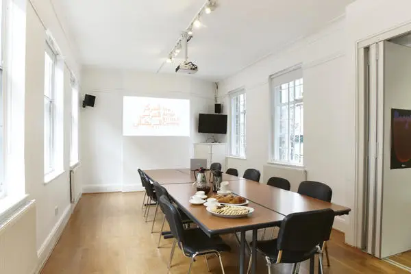 A white room with a long meeting table and chairs. 