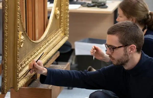 conservators restoring a frame